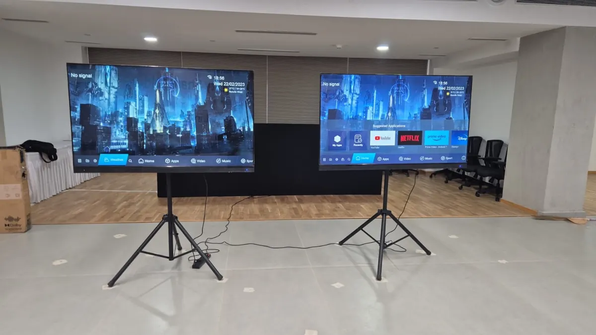 Two LED TVs on floor stands set up for a corporate event